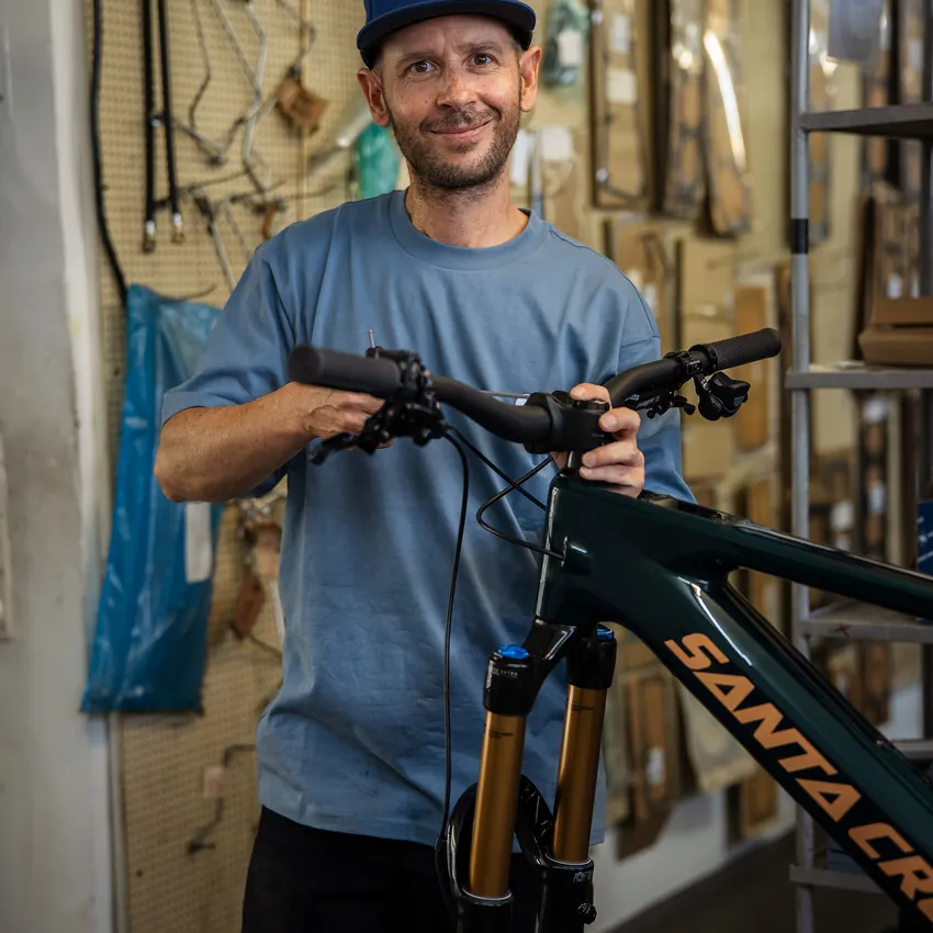 Sportbegeisterter Mitarbeiter mit einem Mountainbike in der Werkstatt