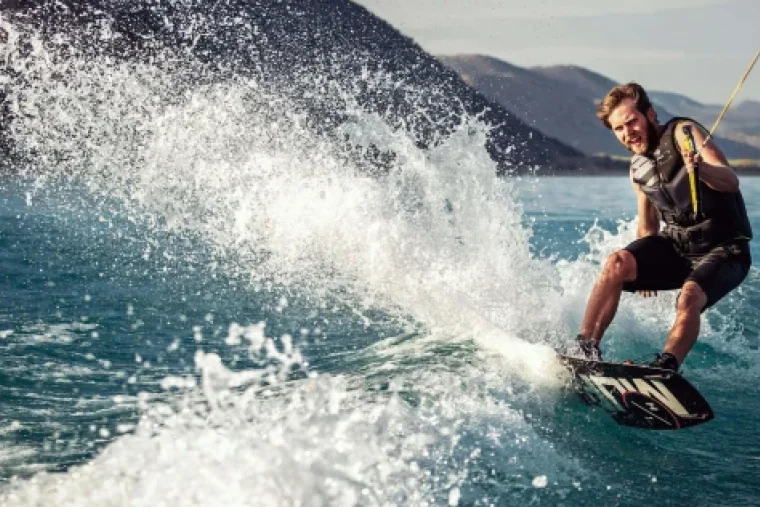 Wakeboarder springt hinter dem Boot über das Wasser